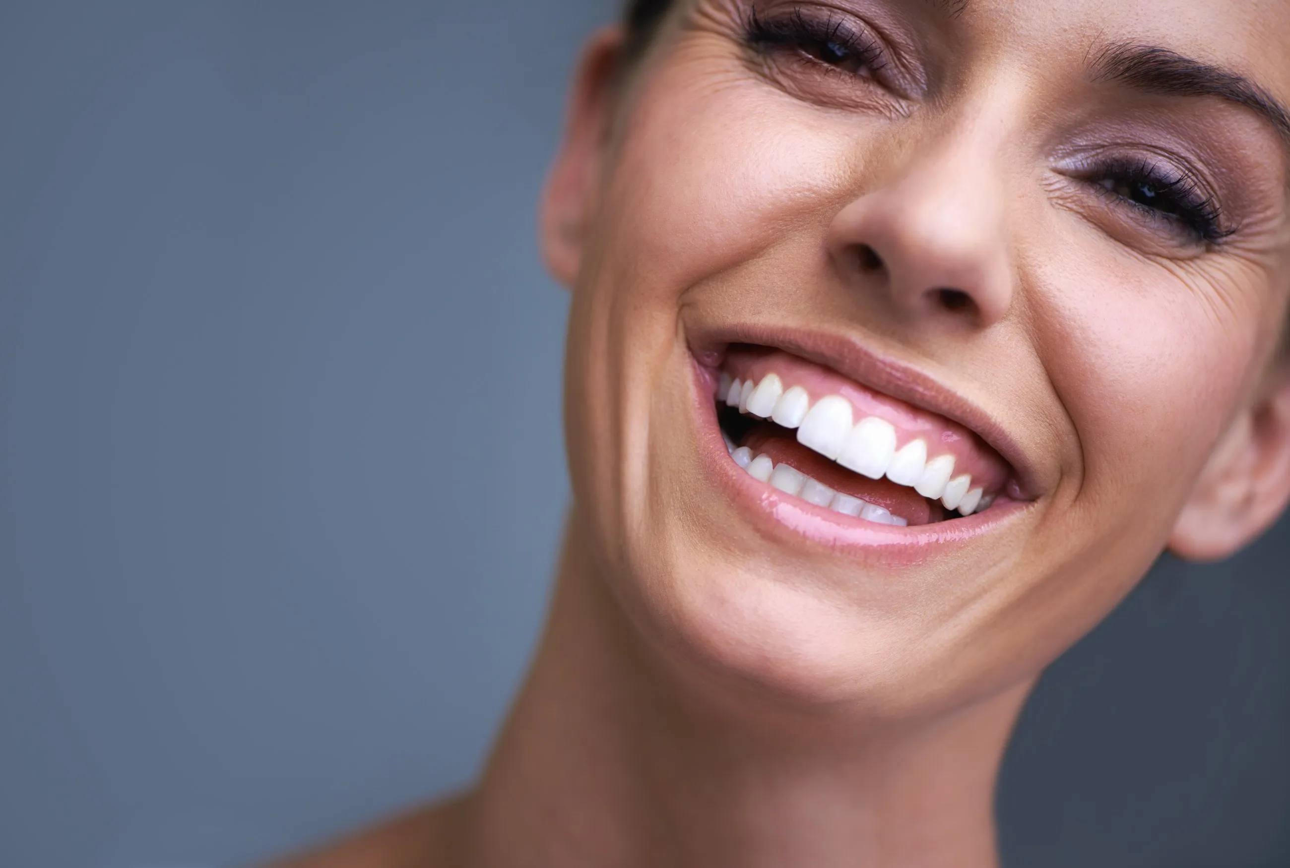 A woman smiling with an even white smile, close up