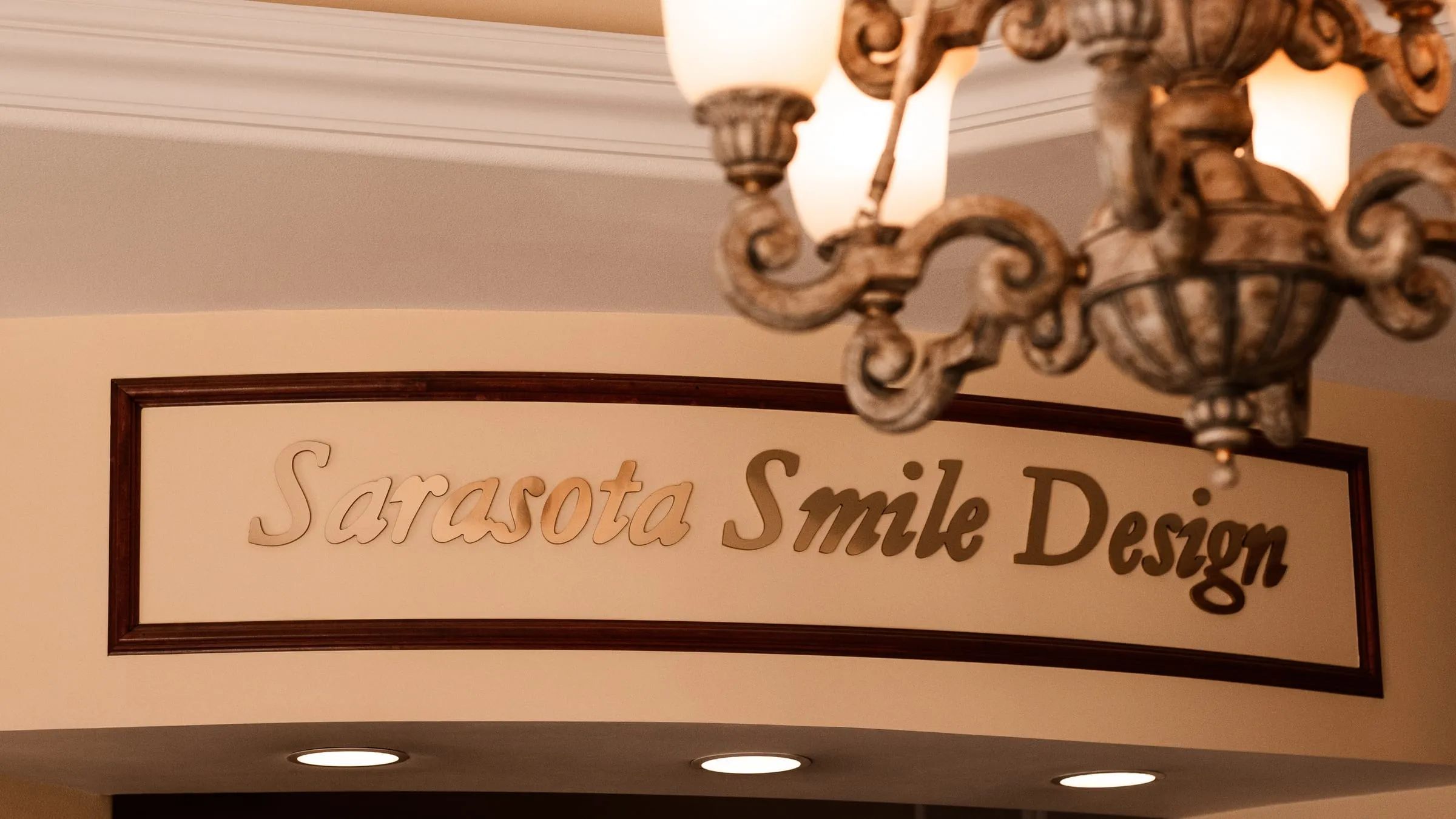The carved Sarasota Smile Design sign under the chandelier in the lobby, Sarasota, Florida