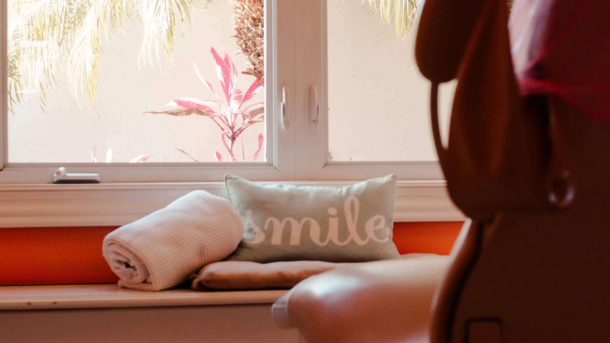 A window bench with a smile pillow and rolled towels at Sarasota Smile Design in Sarasota, Florida