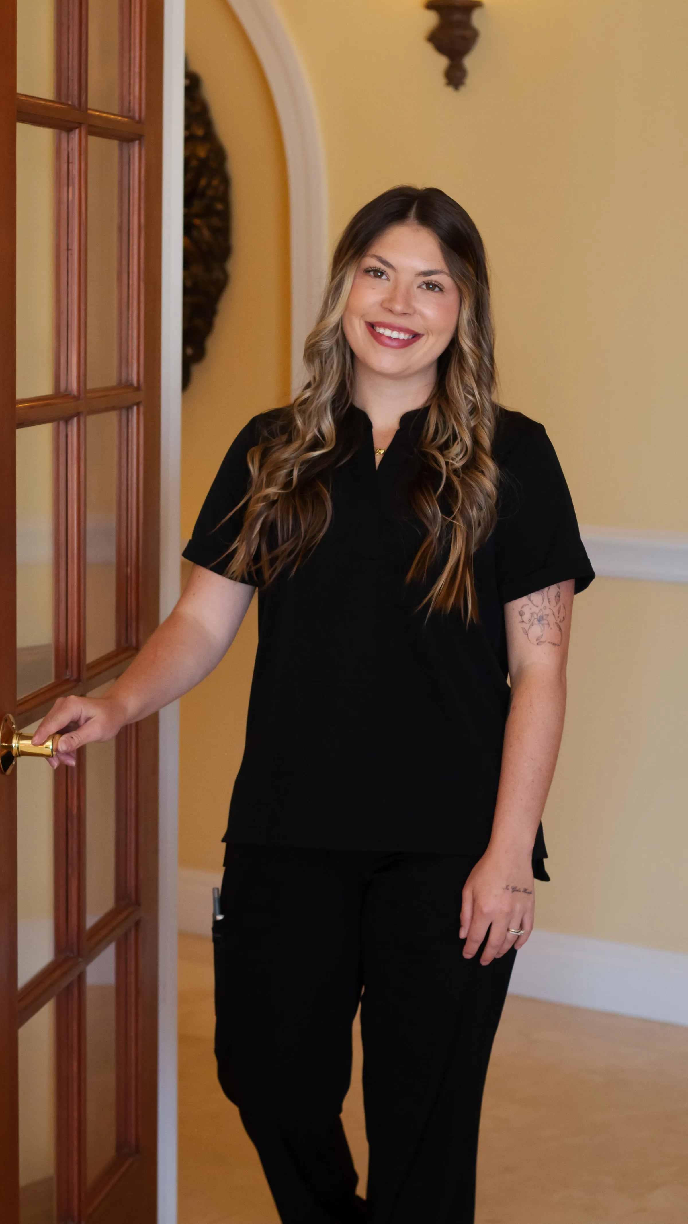 A member of staff opening the door for a patient at Sarasota Smile Design in Sarasota, Florida