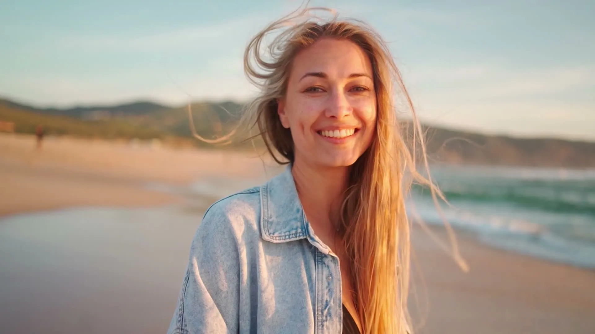 A woman smiling on the beach in late afternoon light
