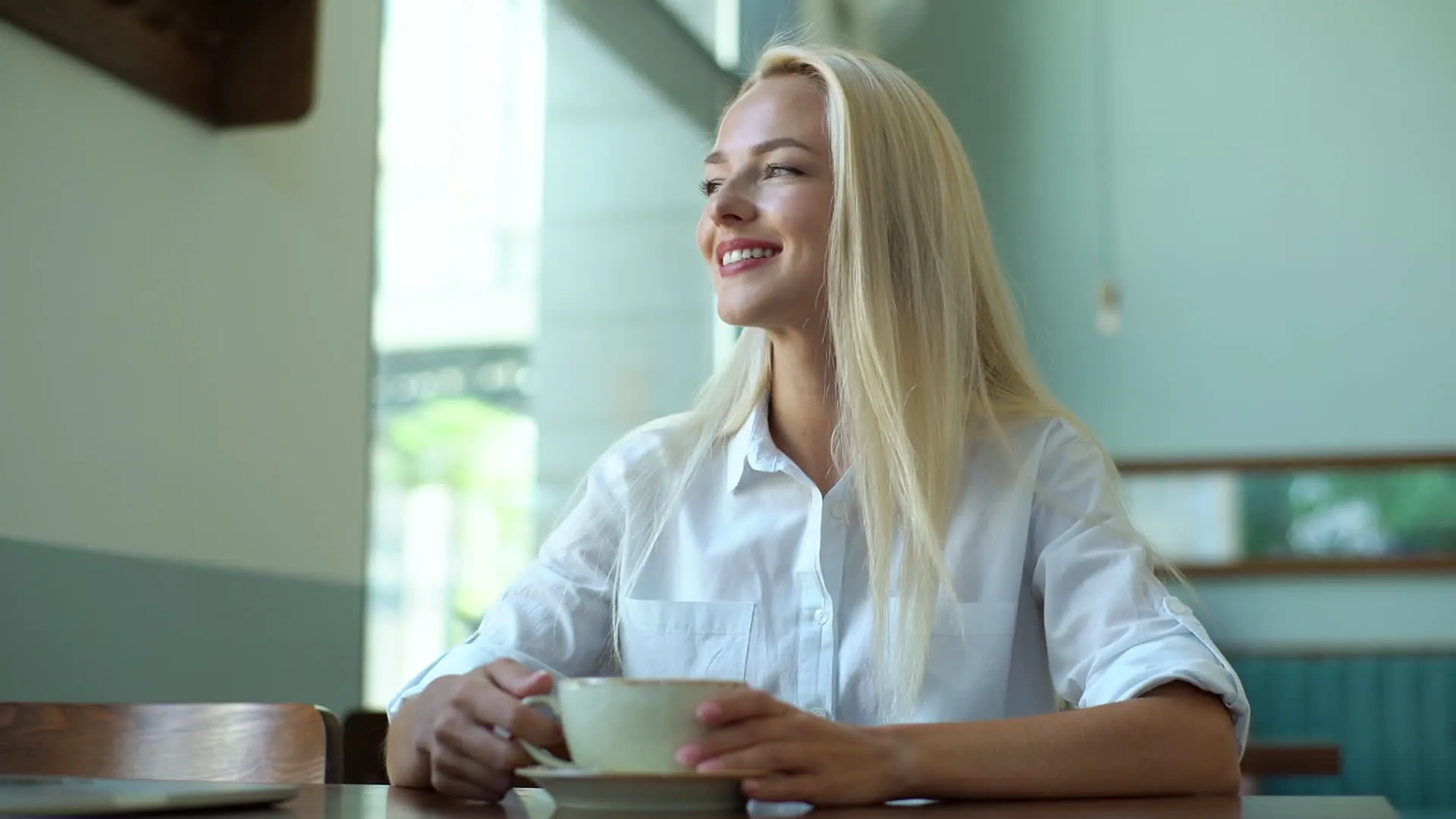 A woman smiling over coffee at a cafe table