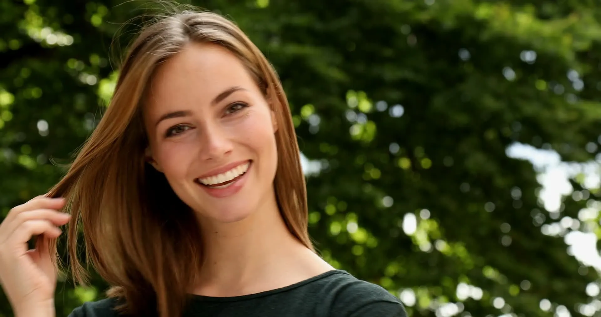 A woman smiling outdoors on a bright day