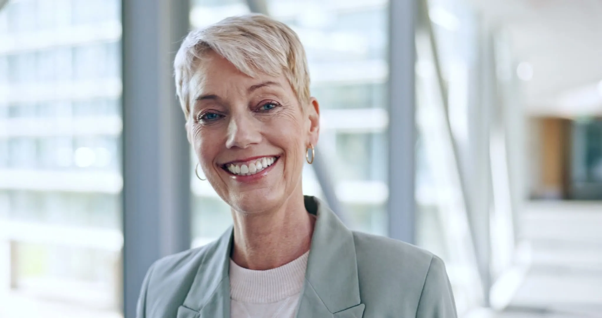 A silver-haired woman smiling in a bright office