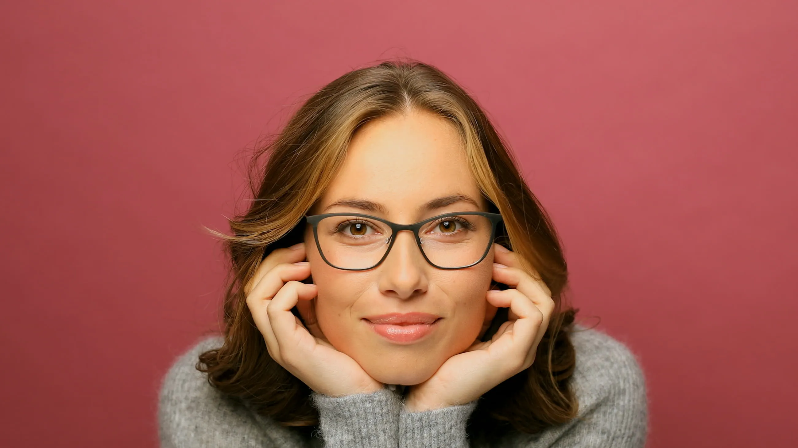 A woman in glasses smiling in a studio portrait