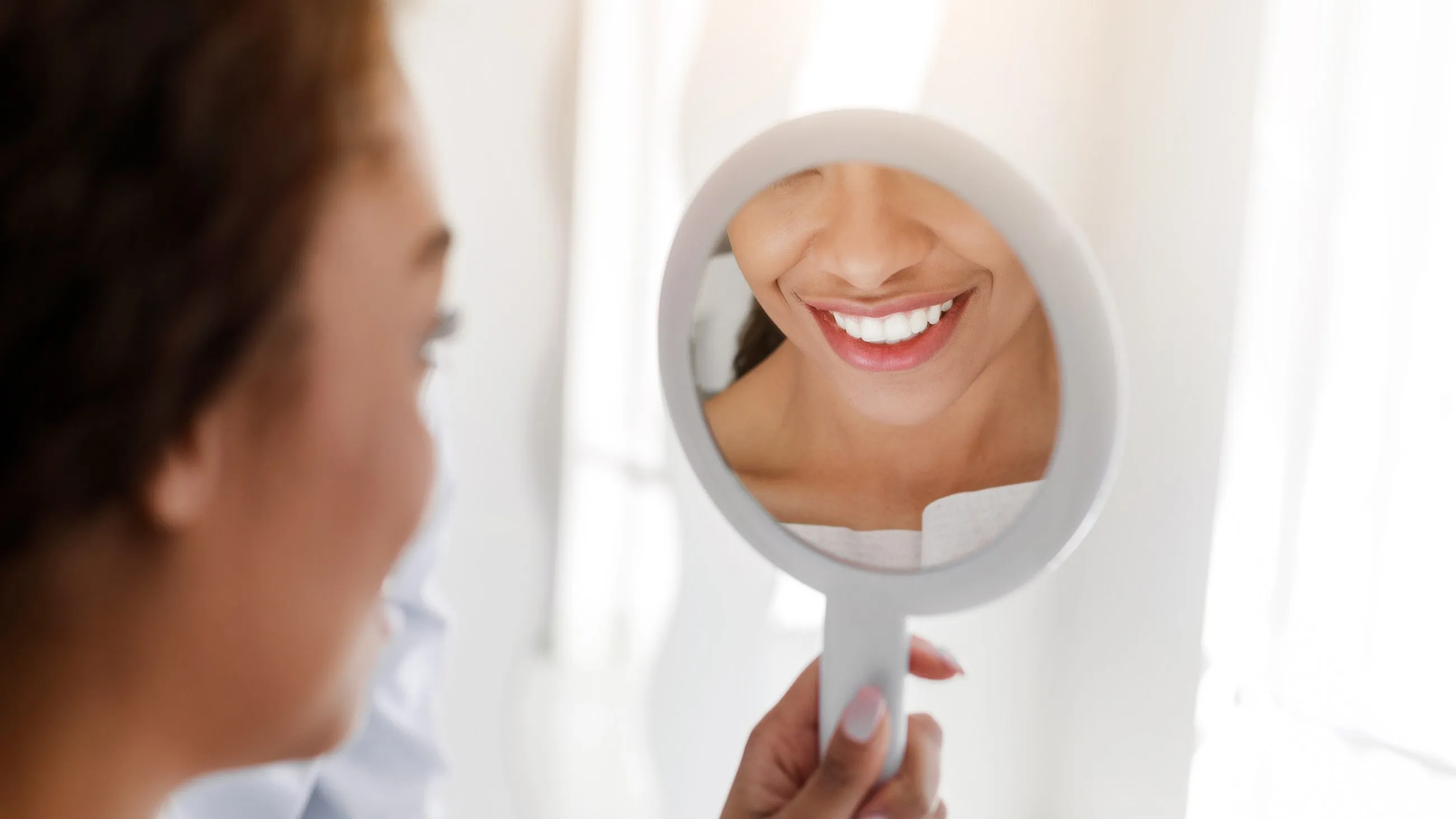 A woman looking at her teeth in a mirror
